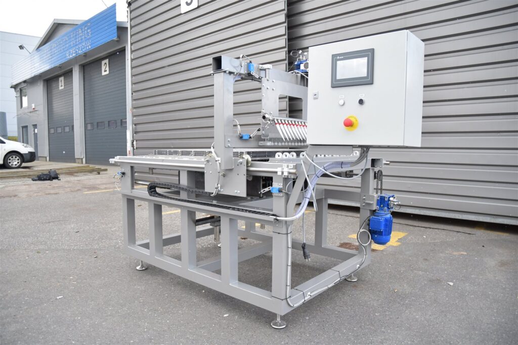 Maszyna stojąca przed ścianą magazynu.